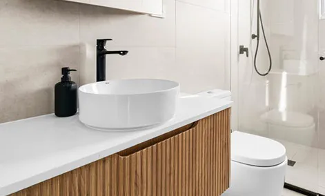 Modern vanity with matte black tapware, round basin, and soft neutral tiles in a Ryde home.