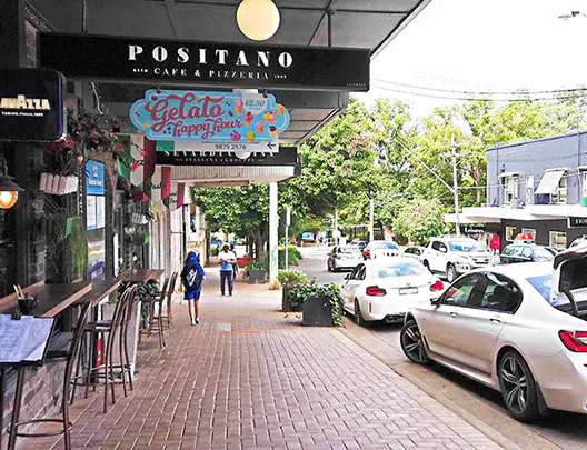 Street view of Beecroft Sydney showing local cafés, boutique shops, and parked cars along the leafy village shopping strip on a sunny day.