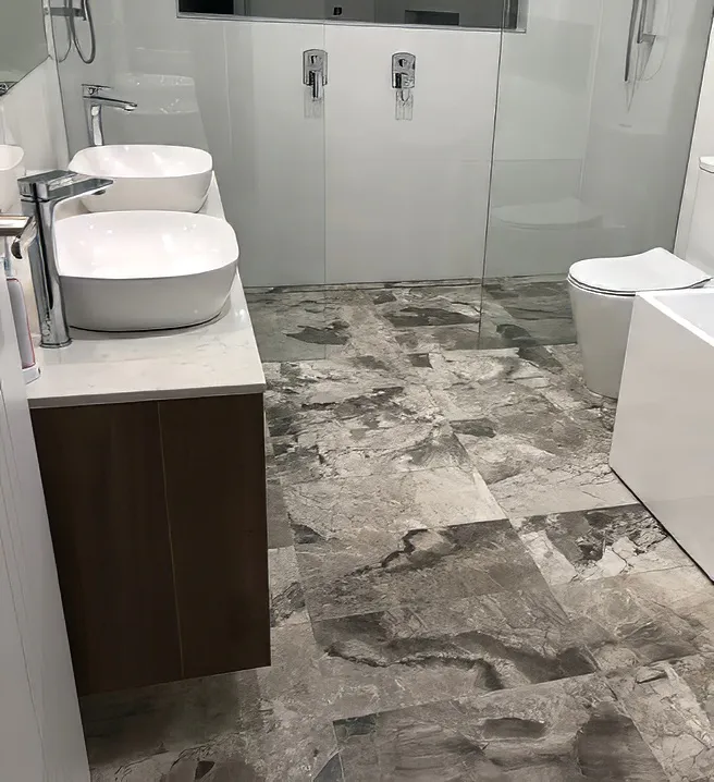 Stylish modern bathroom featuring marble-look floor tiles, white freestanding bath, double vanity with vessel basins, chrome tapware, glass shower enclosure, and minimalist white wall tiles for a sleek, contemporary finish.
