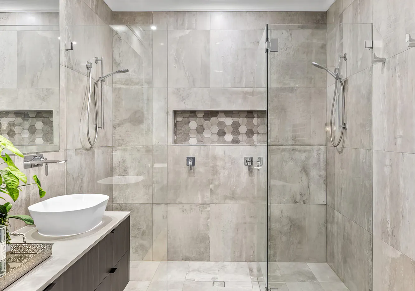 Hero image for Bathroom Renovations Beecroft featuring a modern double shower with frameless glass, grey stone-look tiles, hexagonal mosaic niches, and sleek vanity with white countertop basin.